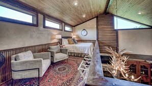 Une pièce confortable avec un lit, une chaise, une horloge et un plafond en bois.