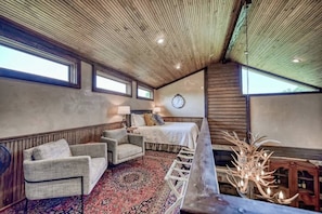 Una habitación acogedora con cama, un reloj, un ventilador y techo de madera.
