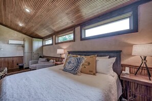 Un dormitorio con una cama grande, techo de madera y una ventana.