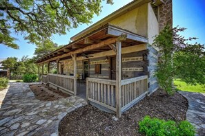 A stone building with a covered porch, stone pathway, and surrounding greenery. - Luxury 23-ac Ranch Casita w/Hot tub! (Fredericksburg)