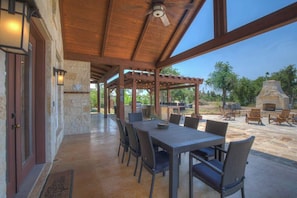 An outdoor patio with a covered seating area, stone flooring, and a stone fireplace. - Lux Ranch w/Pool-Hot-Tub Near Fred! (Fredericksburg)