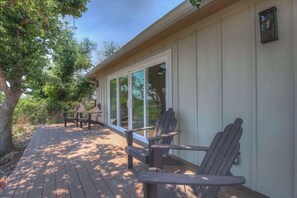 Une terrasse en bois avec des chaises Adirondack et une table, donnant sur un jardin.