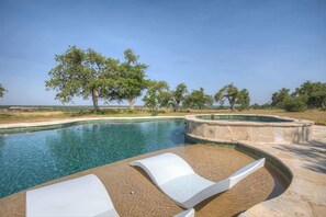 A swimming pool with clear water, surrounded by a stone deck and lounge chairs. - Lux Ranch w/Pool-Hot-Tub Near Fred! (Fredericksburg)