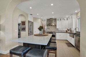 A modern kitchen with a large island, white cabinetry, stainless steel appliances, and recessed lighting. - Lux Ranch w/Pool-Hot-Tub Near Fred! (Fredericksburg)