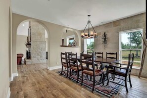 Un coin repas agrémenté d’une cheminée en pierre, d’une table à manger en bois et de chaises.