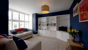 Una sala de estar con un sofá, un televisor y una estantería.