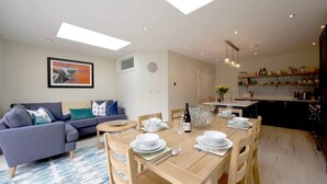 Una sala de estar moderna con un sofá, una mesa de comedor para cuatro personas y una cocina con encimera y armarios.