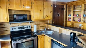 A kitchen with wooden cabinets, a microwave, a stove, a sink, and a ceiling fan. - Cozy lakeside cottage with breathtaking views & amazing fishing  (Yarker)