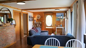 A cozy living room with a wooden ceiling, a dining table with chairs, a sofa, and a fireplace. - Cozy lakeside cottage with breathtaking views & amazing fishing  (Yarker)