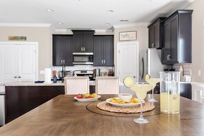 Enjoy meals in this kitchen with a central island, stainless steel appliances, and a dining table.