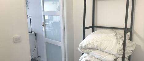 A room with a bunk bed, a white door with frosted glass, and a white wall.