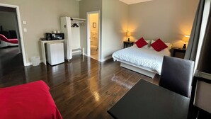 Habitación de hotel con cama, mesitas de noche, escritorio, silla, armario y baño.