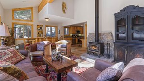 Ein geräumiges Wohnzimmer mit Kamin, Holzmöbeln und Blick in die Küche.
