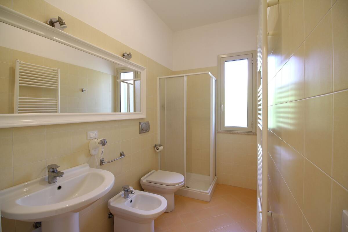 A bathroom with a sink, bidet, toilet, and a walk-in shower.