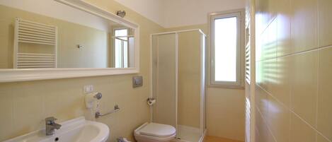 A bathroom with a sink, bidet, toilet, and a walk-in shower.