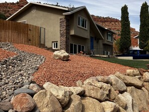 Una casa moderna de dos pisos con fachada de piedra, ventanas grandes y un jardín delantero bien cuidado con rocas y grava.