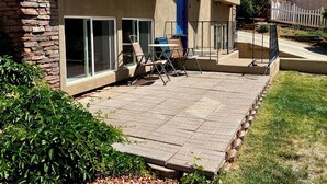 A patio with outdoor furniture, a stone wall, and a view of a hillside.