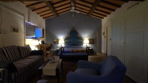 Een slaapkamer met een bed, een bank, een stoel, een bureau en een plafondventilator.
