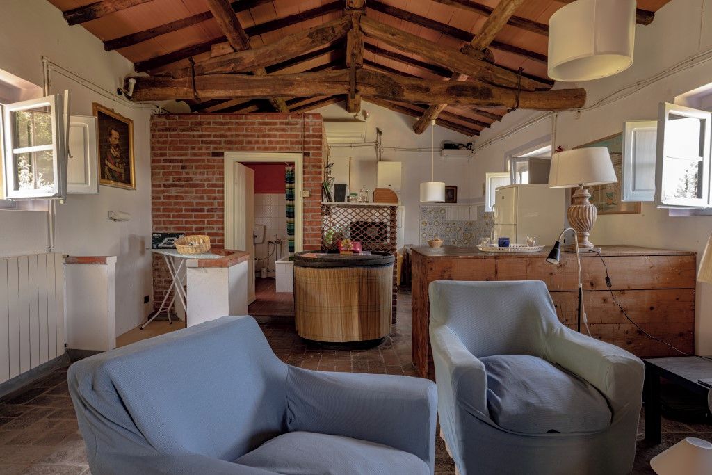 A rustic interior with exposed wooden beams, a brick wall, and a round wooden table.