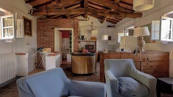 A rustic interior with exposed wooden beams, a brick wall, and a round wooden table.