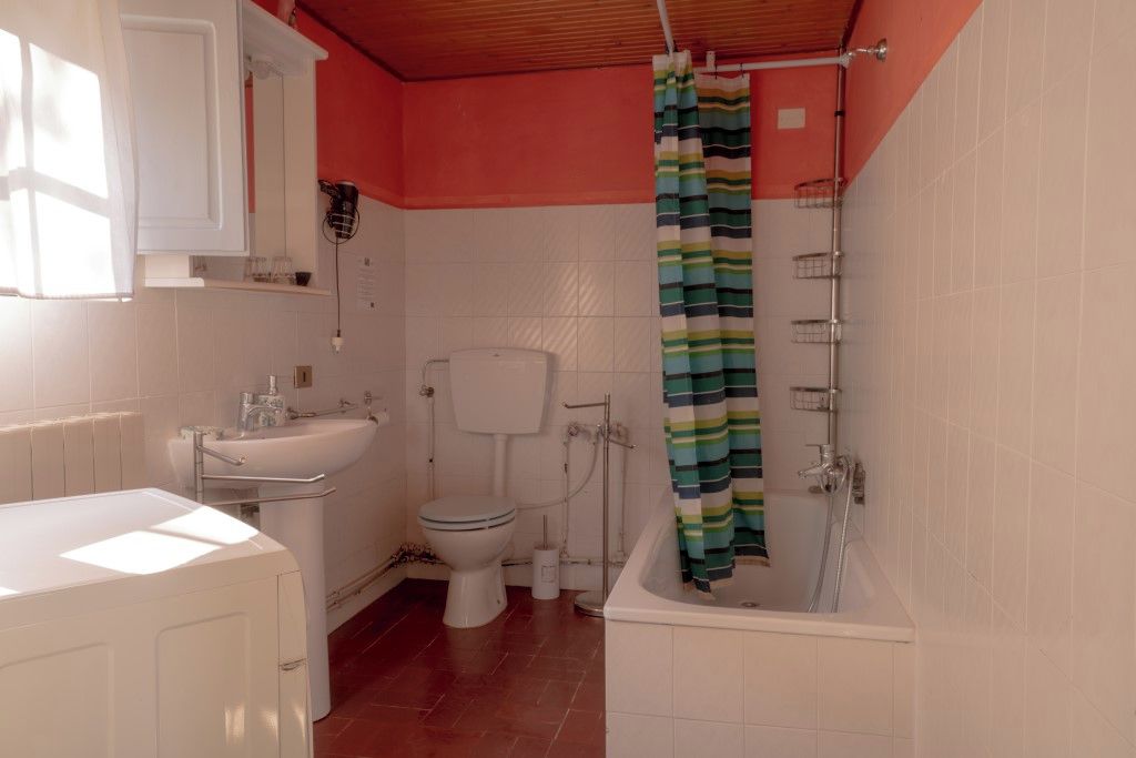 A bathroom with a toilet, sink, bathtub, and shower curtain.