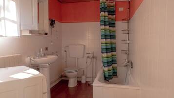 A bathroom with a toilet, sink, bathtub, and shower curtain.