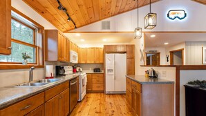 A kitchen with wooden cabinets, a refrigerator, a microwave, and a sink.
