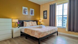 Una camera d'albergo con un letto, comodini, una ventola a soffitto e una finestra con tende.