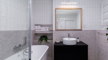 Een moderne badkamer met een vrijstaand bad, een wastafelmeubel met een wastafel en een spiegel erboven.
