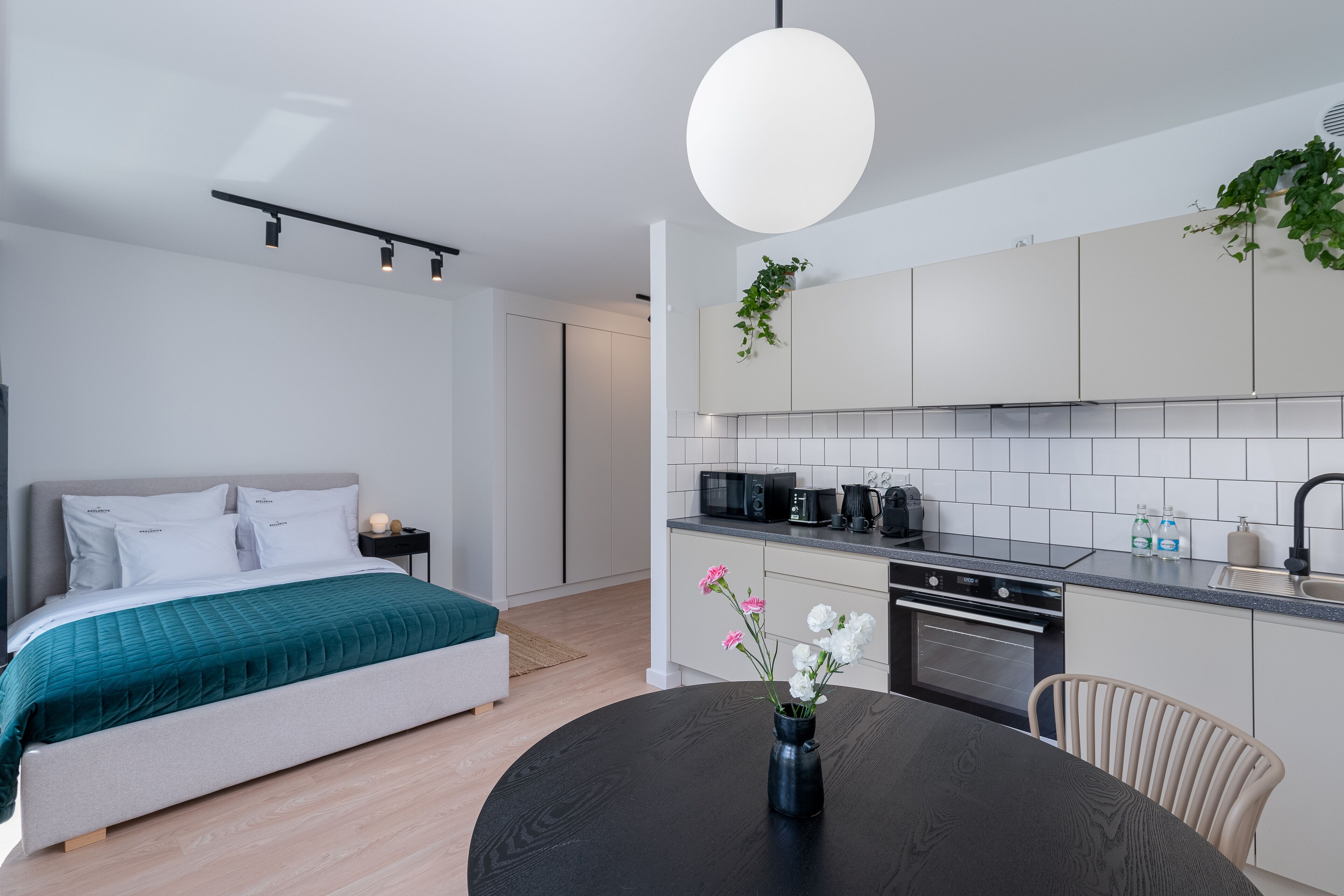 Un dormitorio moderno con cama, mesita de noche y una pequeña mesa con un jarrón de flores.
