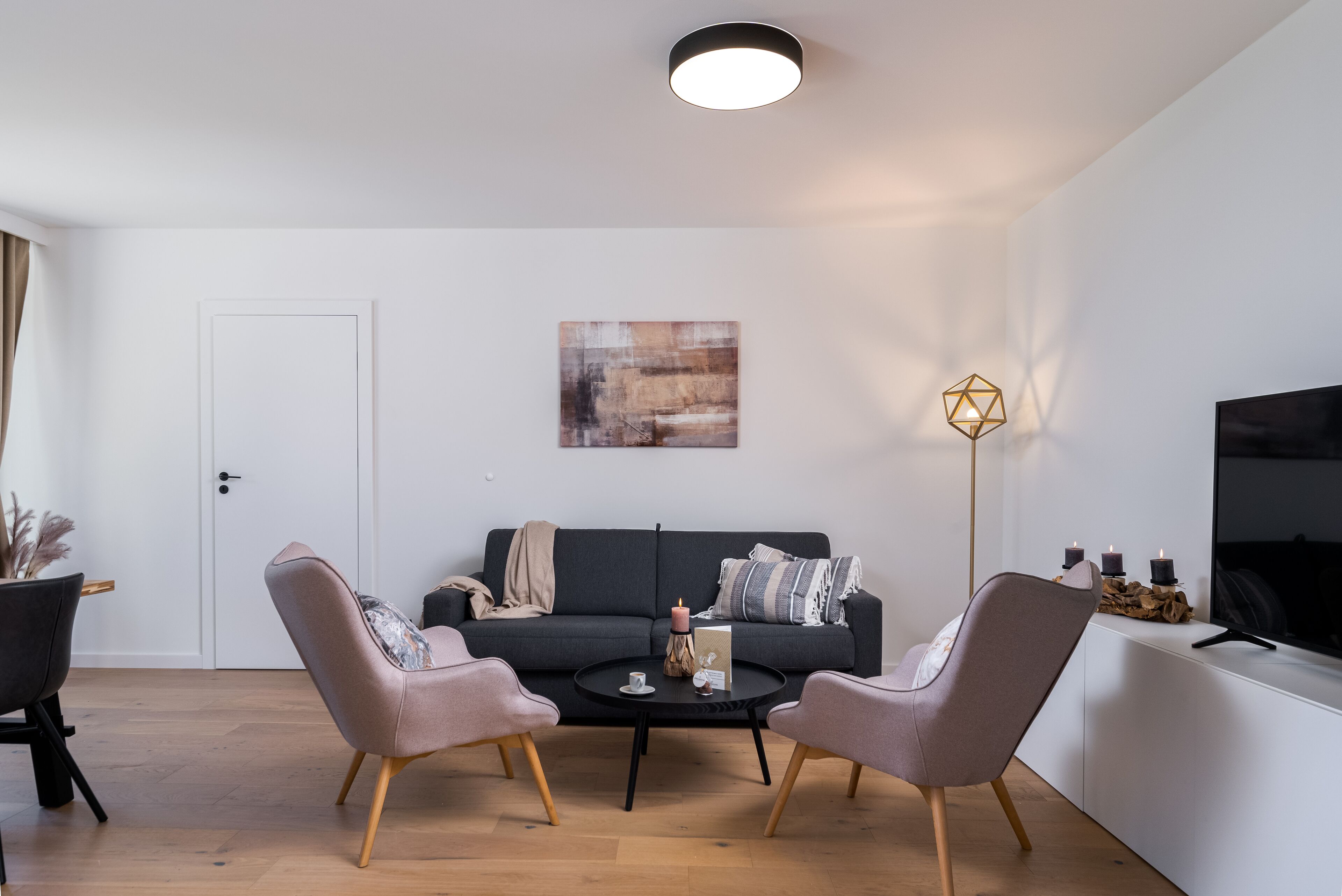 Un salon moderne comprenant un canapé, deux fauteuils, une table basse et un téléviseur.