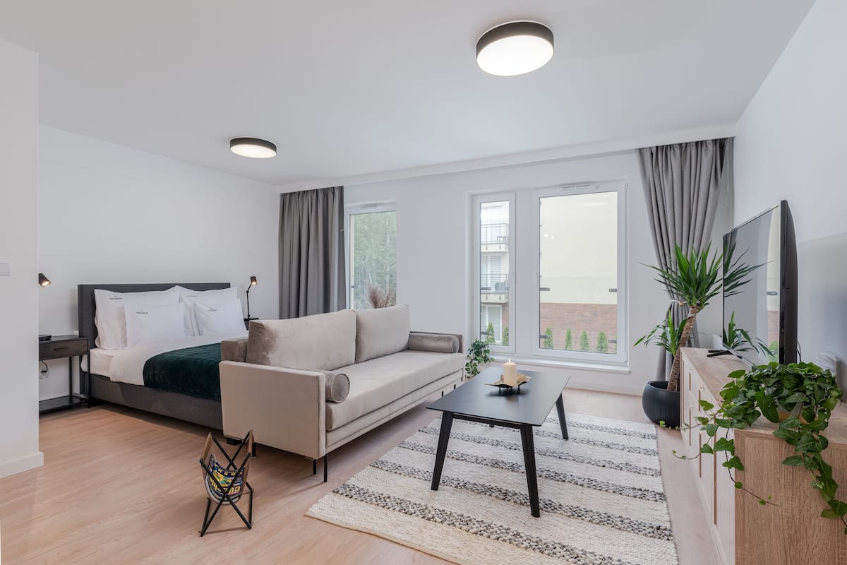 Une pièce moderne et bien éclairée, comprenant un lit, un canapé et une table basse.