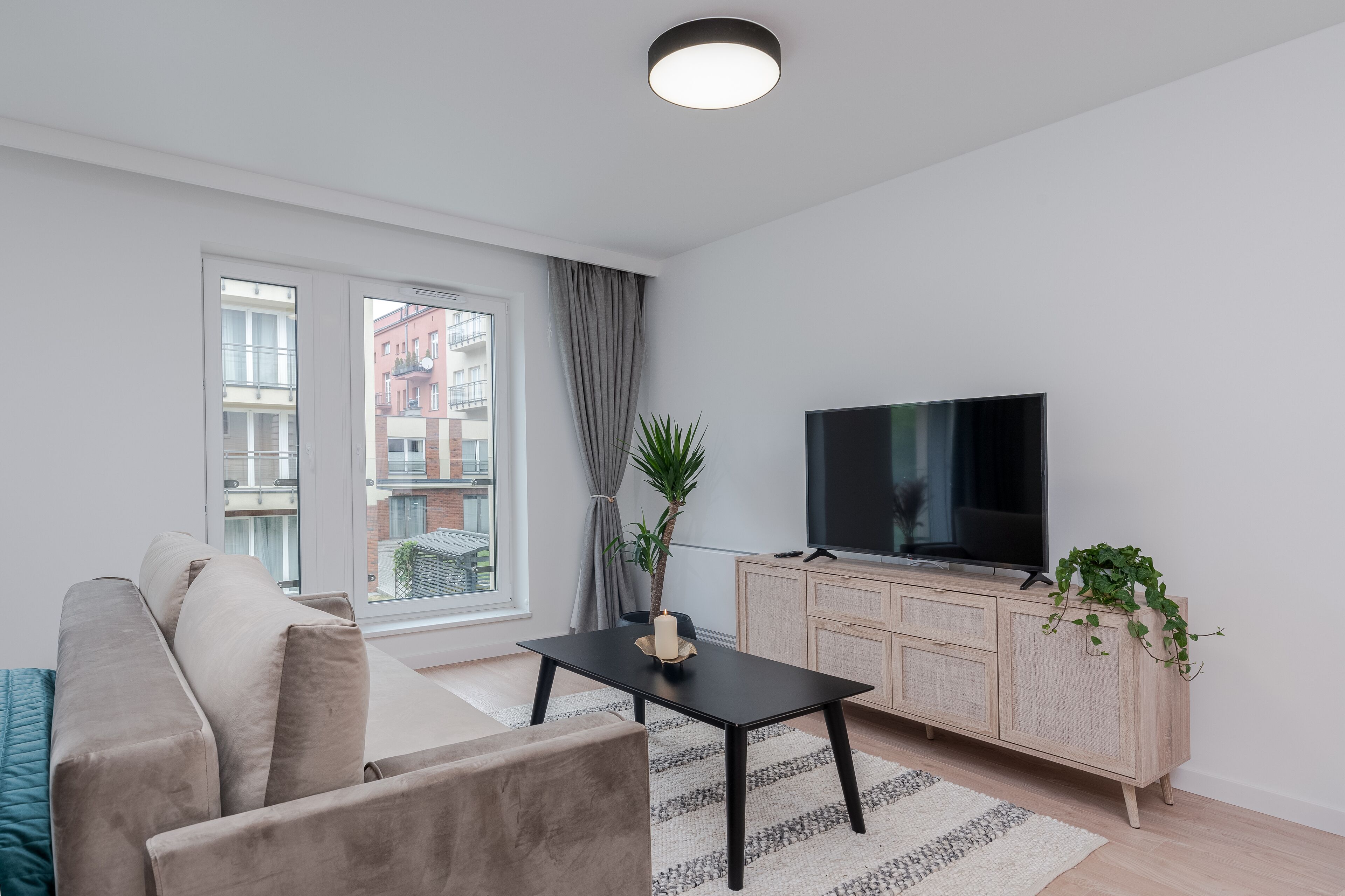 Een moderne woonkamer met een bank, een salontafel, een televisie en een kast.