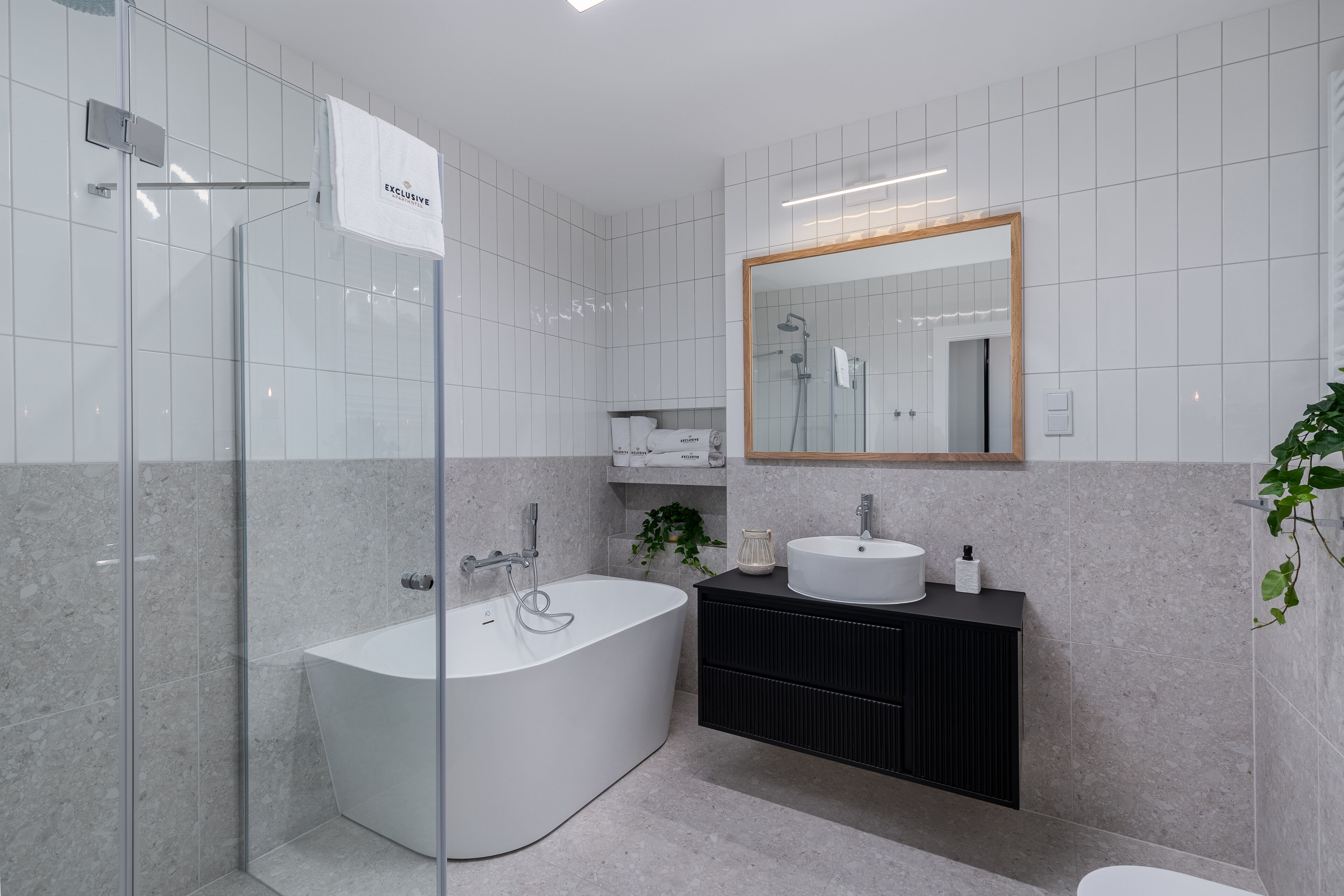 A modern bathroom with a freestanding bathtub, a black vanity with a white sink, and a large mirror above the vanity.