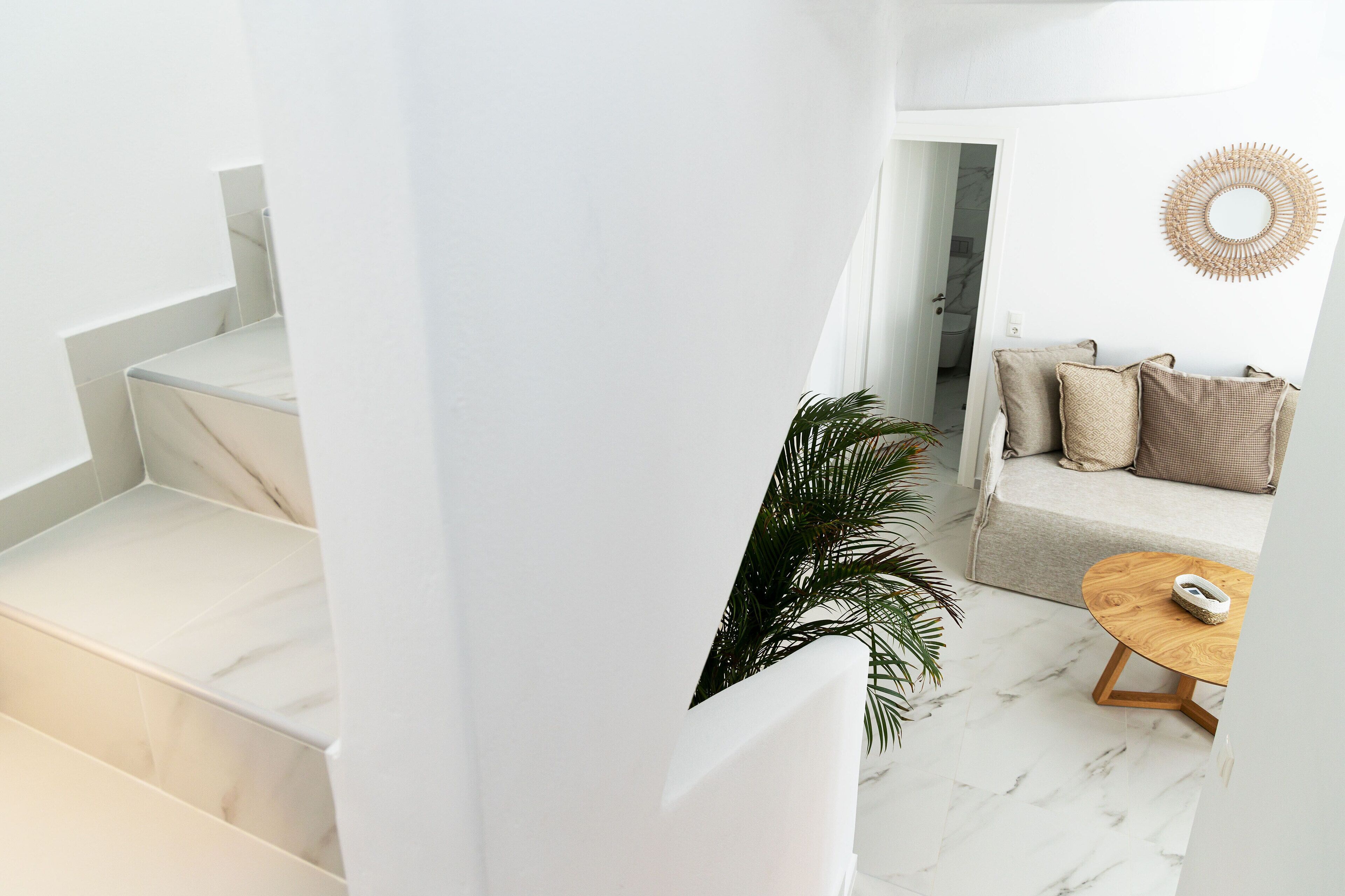 A modern interior with a staircase, a sofa, and a round wooden table.
