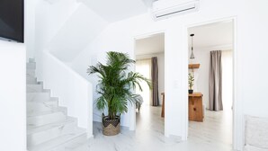 Un interior moderno con una escalera, una planta en maceta y un área de comedor.