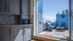 A modern kitchen with grey cabinets, a stainless steel sink, and a microwave. - Ramsey Apartment - 2 Bedroom Apartment - Tenby (Tenby)