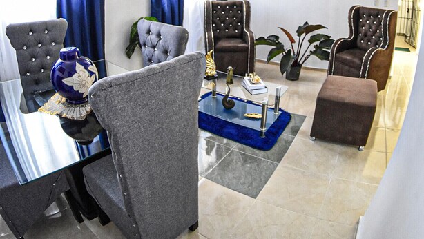 A modern living room with a dining area, featuring tufted chairs, a glass coffee table, and a chandelier. - Apartment in the races near the monument (Santiago De Los Caballeros)