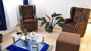 A living room with two brown leather armchairs, a glass coffee table, and a blue shag rug. - Apartment in the races near the monument (Santiago De Los Caballeros)