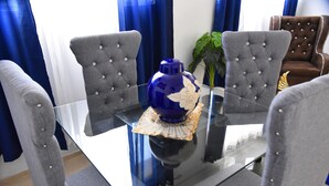 A dining table with a blue vase, surrounded by grey upholstered chairs. - Apartment in the races near the monument (Santiago De Los Caballeros)