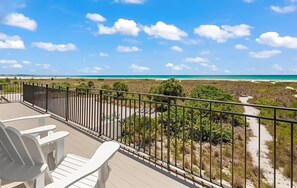 A balcony with a view of a beach and ocean.