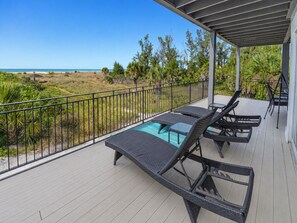 A covered outdoor area with a pool, lounge chairs, and a view of the beach. - Spacious 3BR townhome w/ easy beach & pool access (Siesta Key)