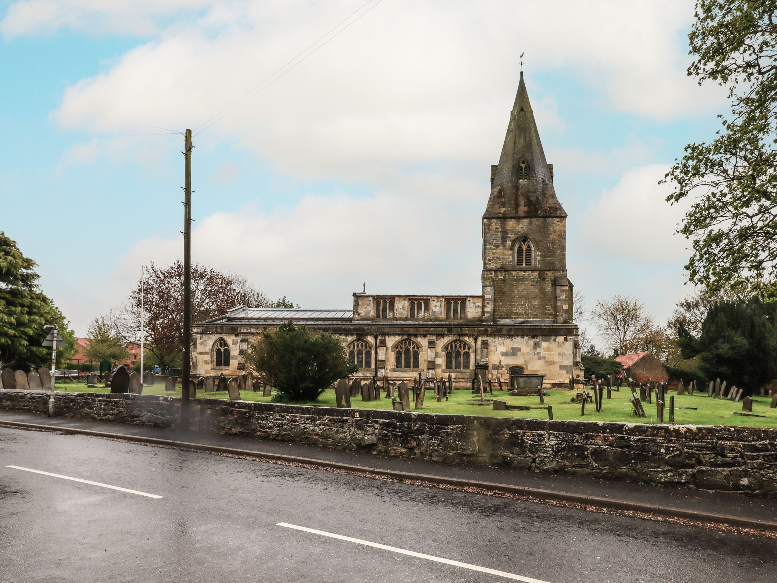 A historic church with a tall spire, surrounded by a cemetery with headstones.