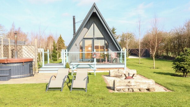 Une maison moderne de style « A », dotée d’une terrasse, de chaises longues et d’un jacuzzi.