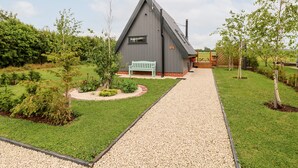 Un bâtiment moderne doté d’un toit en pente, d’un chemin de gravier menant à un banc et d’un panneau indiquant la présence d’un restaurant.