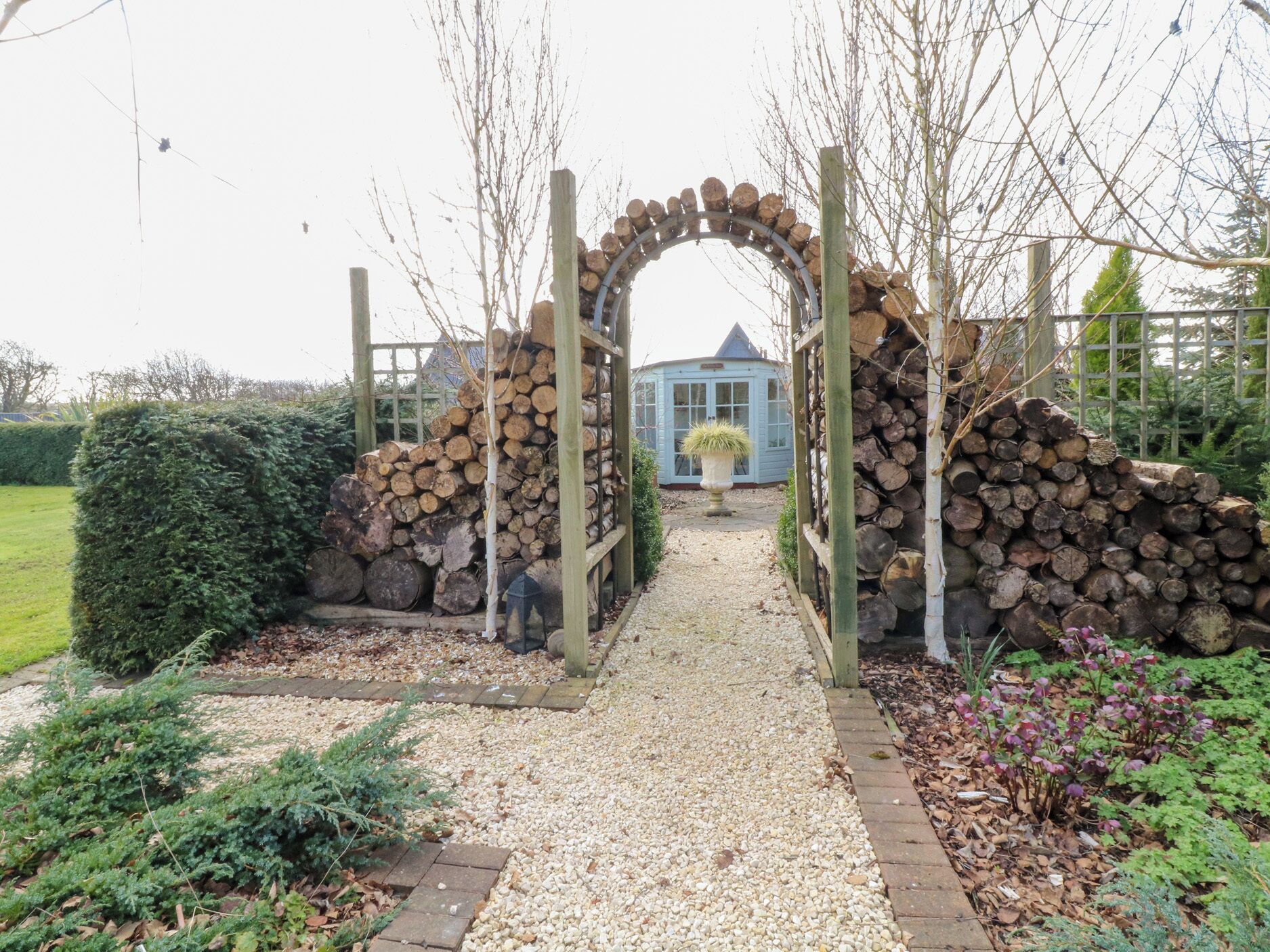 A garden pathway leading to a blue house with a wooden archway.