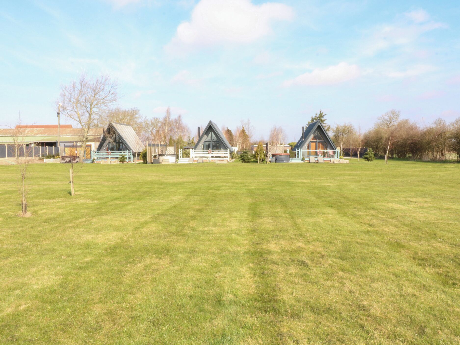A large grassy field with three modern houses with sloped roofs.