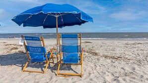 Two blue beach chairs with a blue umbrella on a sandy beach. - Seagrove Villa 11C - Extreme Oceanfront! Resort! (Isle of Palms)
