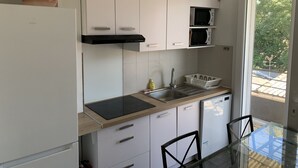 Een moderne keuken met witte kasten, een zwart aanrecht en een glazen tafel.