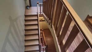 Eine Holztreppe mit Handlauf, die zu einem Raum mit einem großen Fenster führt.